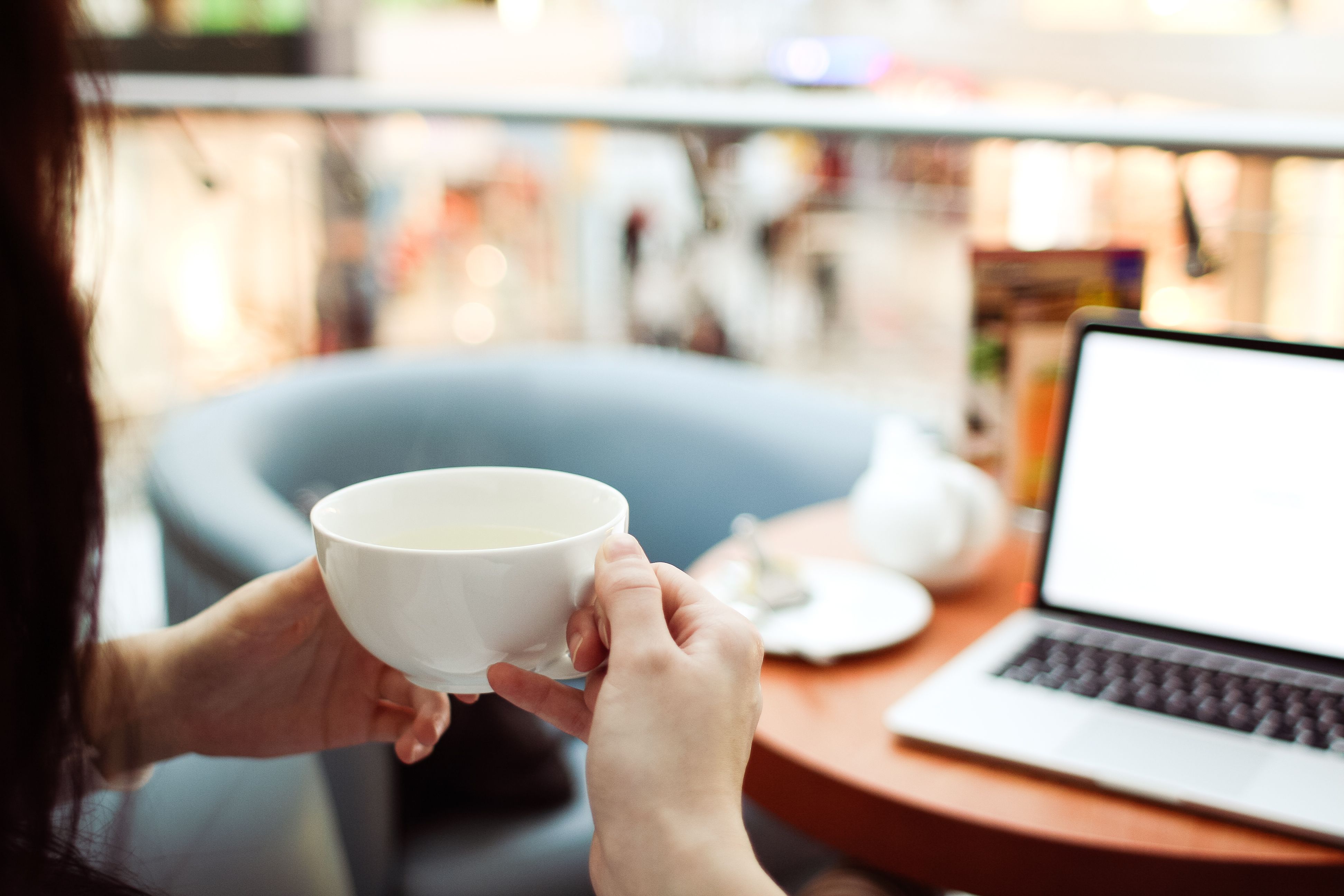 A person working on a laptop at a cafe with a cup of coffee, illustrating the digital nomad lifestyle in Bali